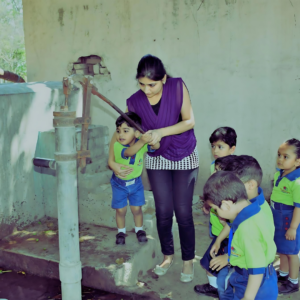 Child using hand pump during farm land excursion at The Nurtuary Preschool, top preschool in Sector 20 Panchkula