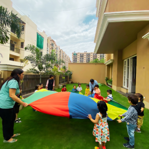 Kids playing with a colorful parachute at The Nurtuary Preschool, Sector 20, Panchkula